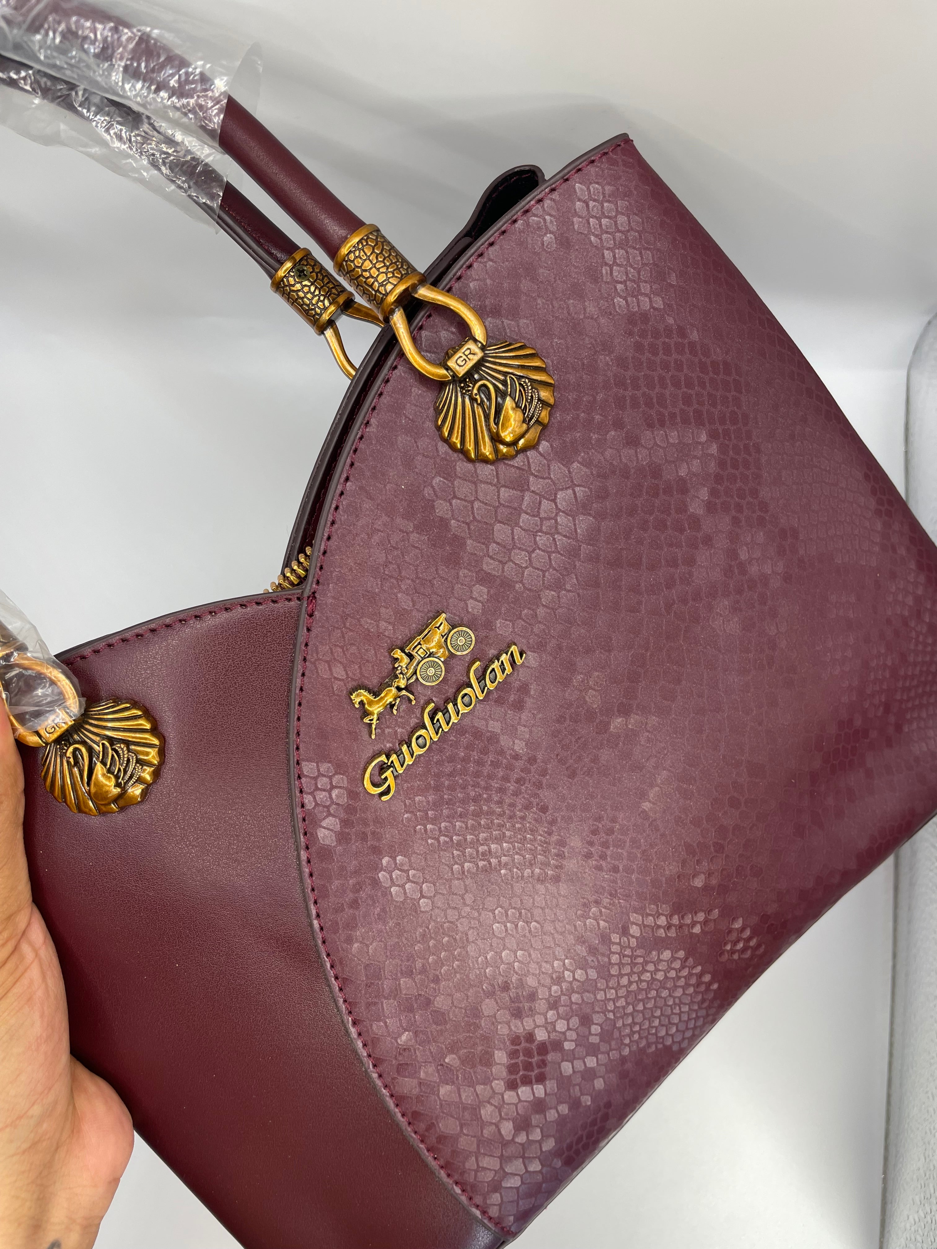 This is a Guoluolan burgundy top handle bag with a snakeskin-textured panel.